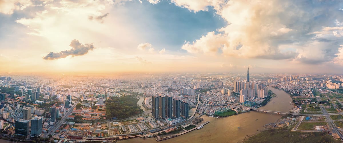 A panoramic view of a city with a river, high-rise buildings, and a prominent skyscraper.