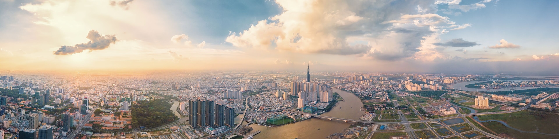 A panoramic view of a city with a river, high-rise buildings, and a prominent skyscraper.