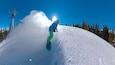 A snowboarder on a snowy slope with trees in the background.