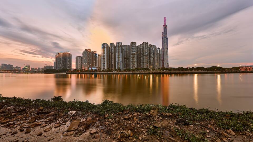 A city skyline at dusk with a river in the foreground.
