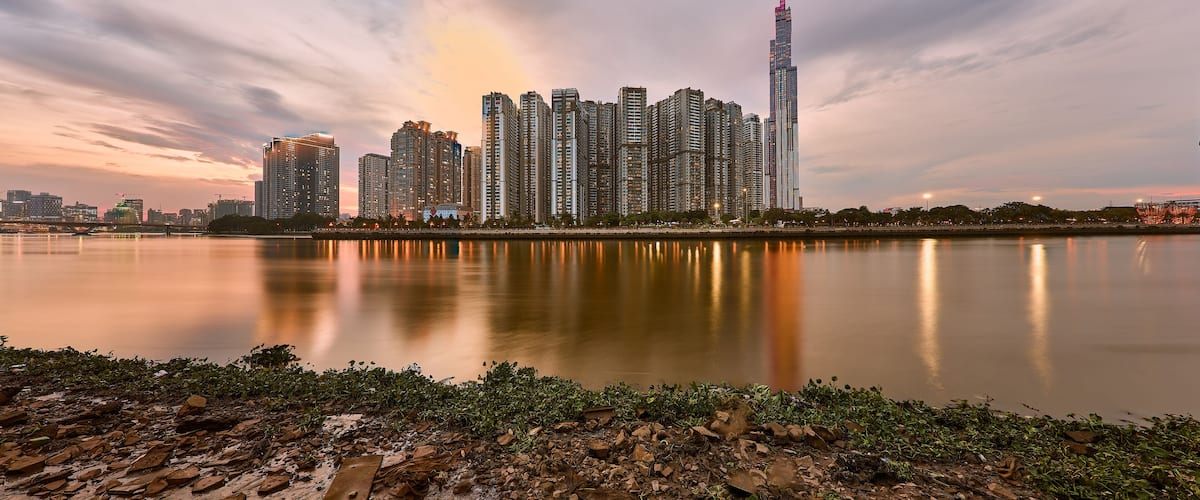 A city skyline at dusk with a river in the foreground.