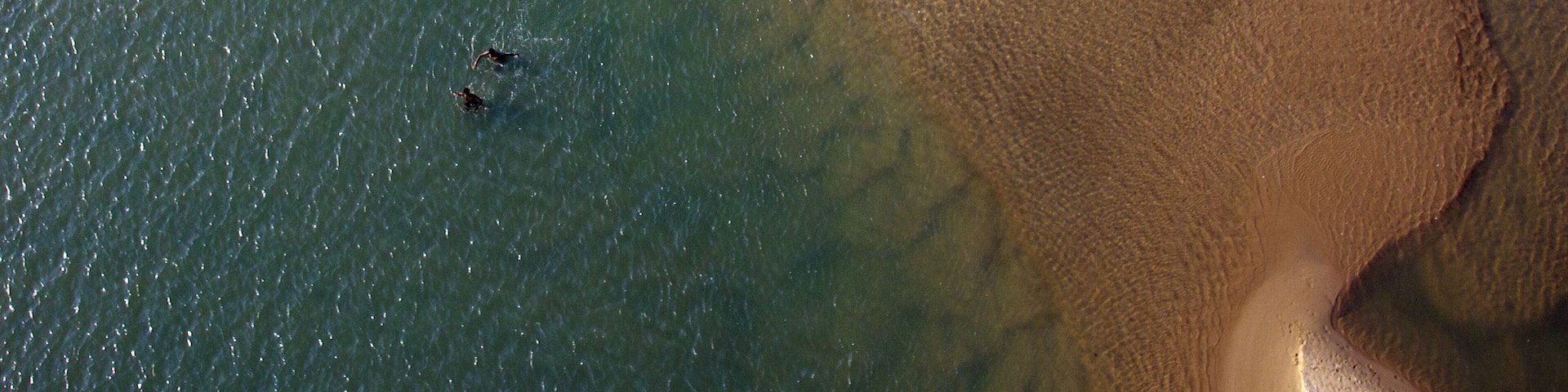 A beach with clear water and a sandy shore.
