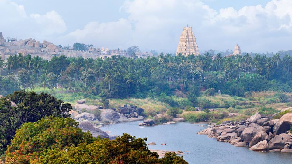 A river winding through a rocky landscape with dense greenery and a prominent temple in the distance.