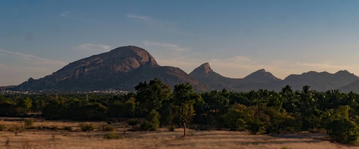 A mountainous landscape with a prominent peak and a valley with scattered trees.