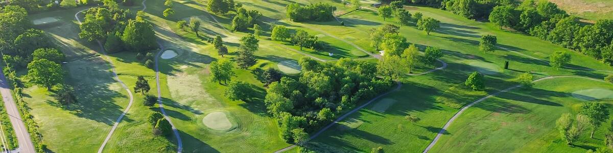 Country golf course with small town warehouses storage and water tower in distant background, municipal golf course country club in Mountain Grove, Missouri, scenic aerial view 18 holes golf