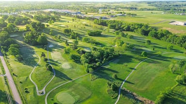 Vista aérea de um campo de golfe com vários greens, fairways e um obstáculo aquático.