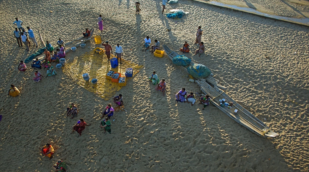 A sandy beach with people, boats, and colorful containers.