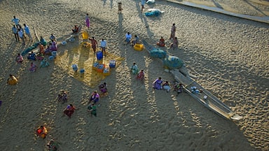 A sandy beach with people, boats, and colorful containers.