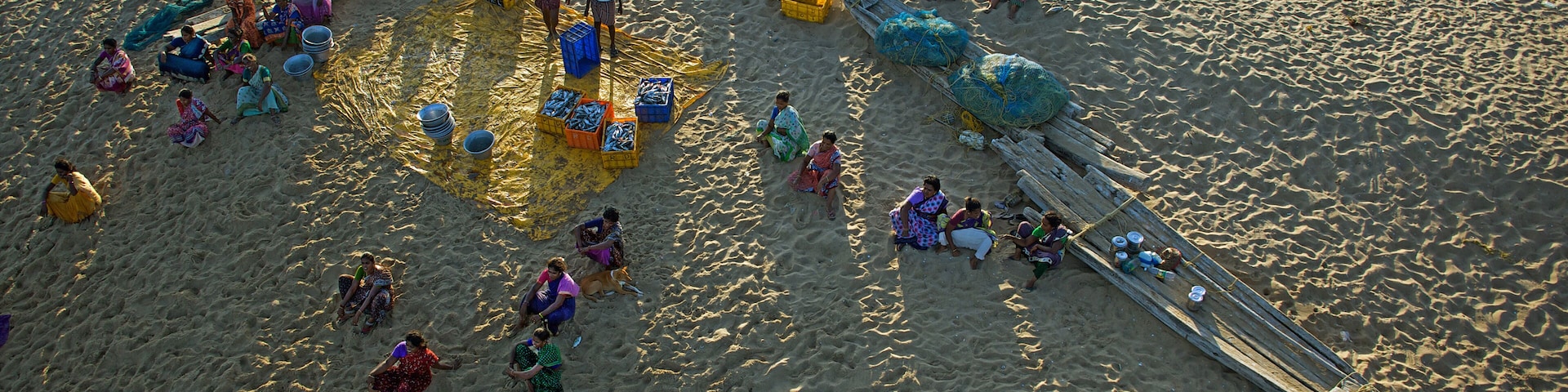 Una playa arenosa con gente, barcos y contenedores de colores.