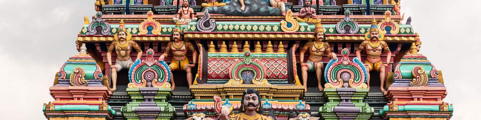 A colorfully decorated tower with mythological figures and deities in an ancient Hindu temple in Tamil Nadu.