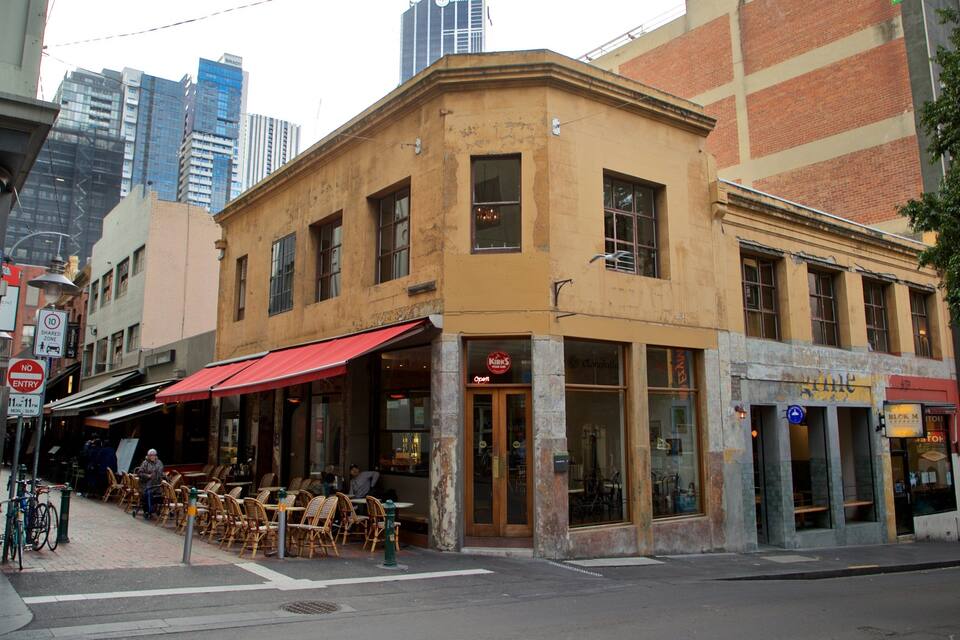 A street corner with a yellow building, outdoor seating, and a red awning.