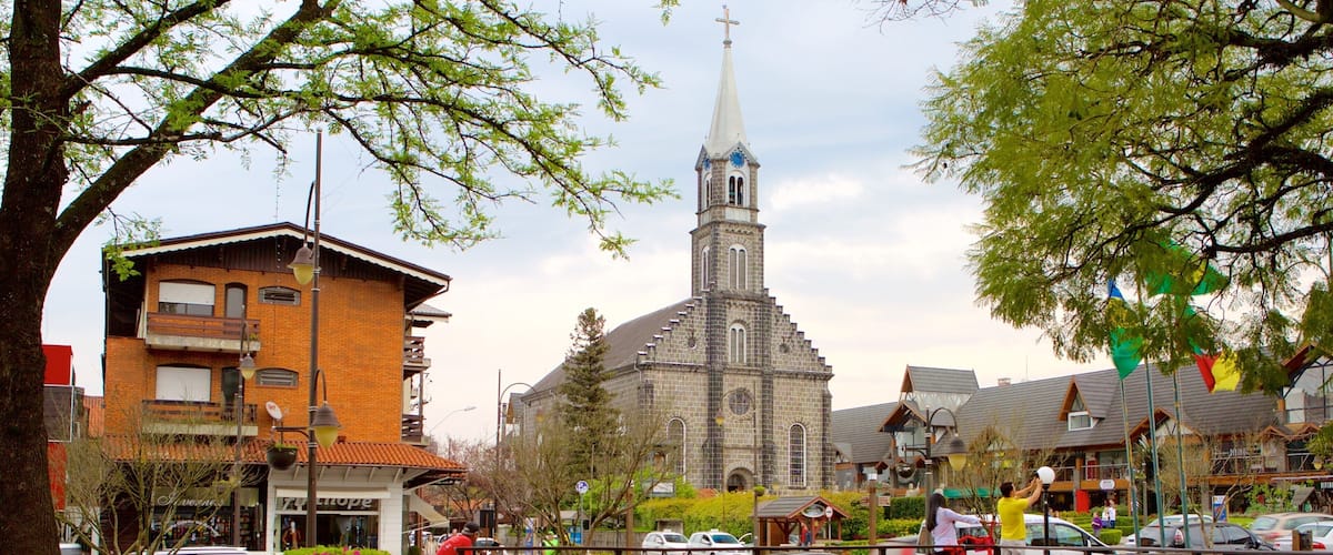 A church with a tall steeple, a brick building with a sign, and a street with cars and a bicycle.