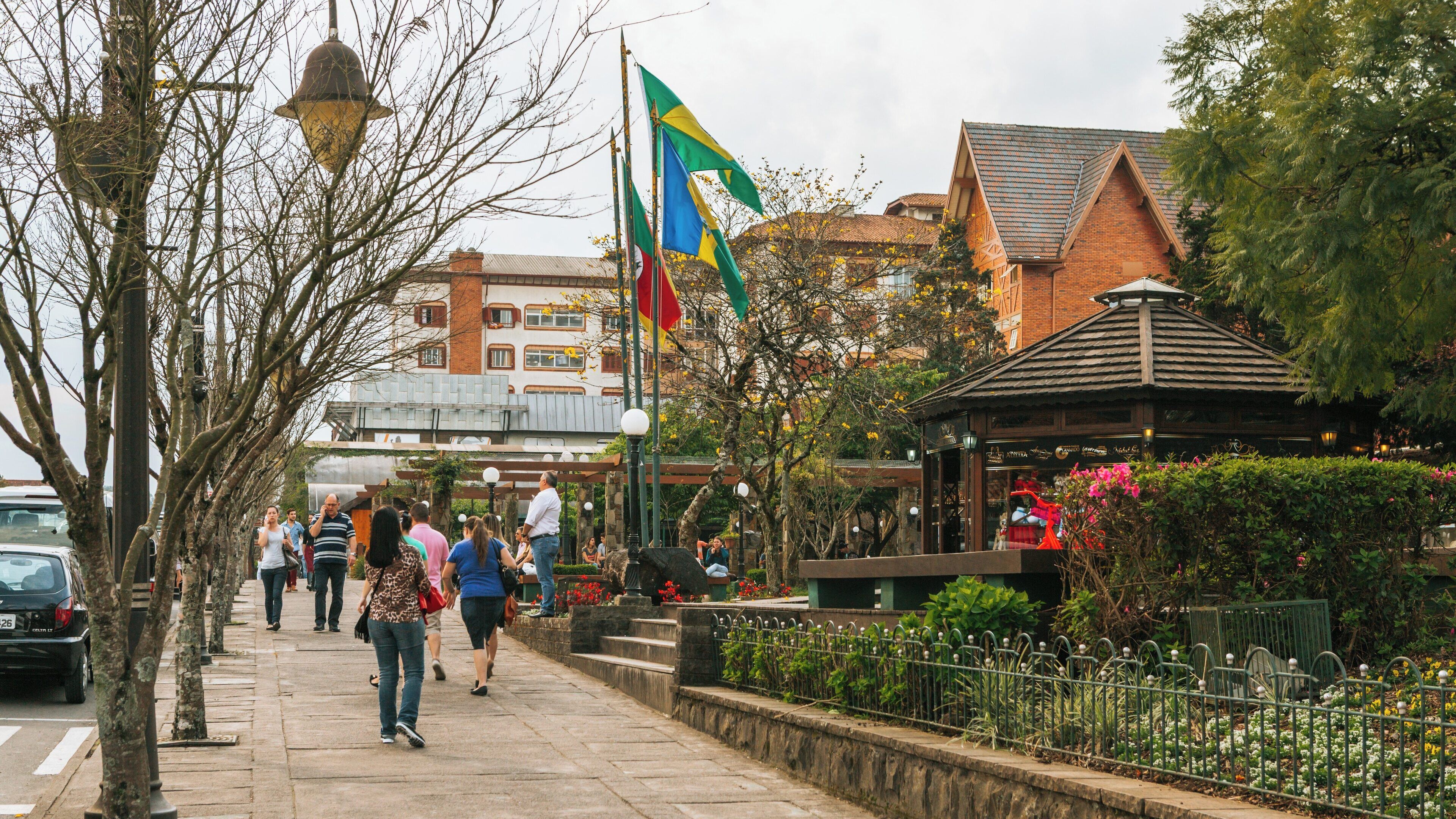 Explore Nicoletti Square in Gramado City Centre, where visitors enjoy leisurely strolls amidst charming architecture and vibrant flags