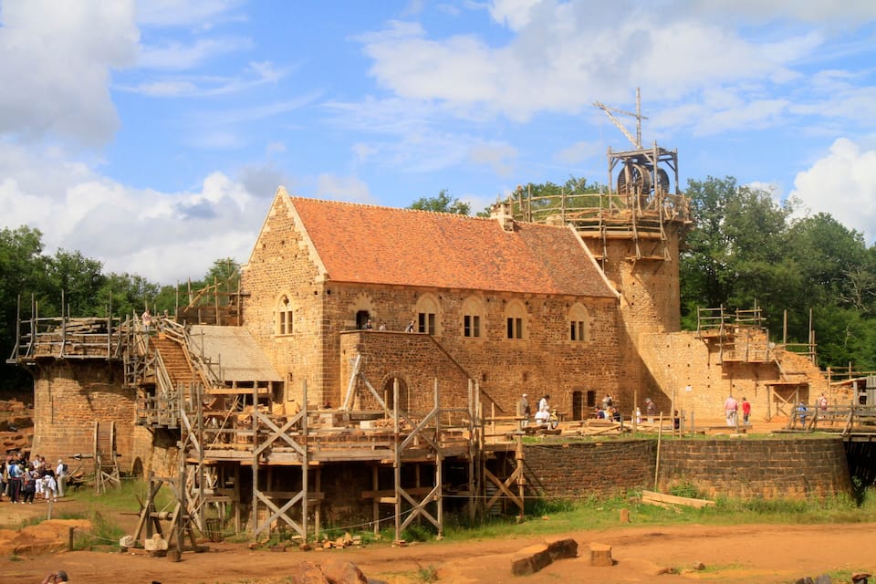Edifici històric amb teulada de rajola vermella i parets de pedra, envoltat d'escafalçats i materials de construcció.