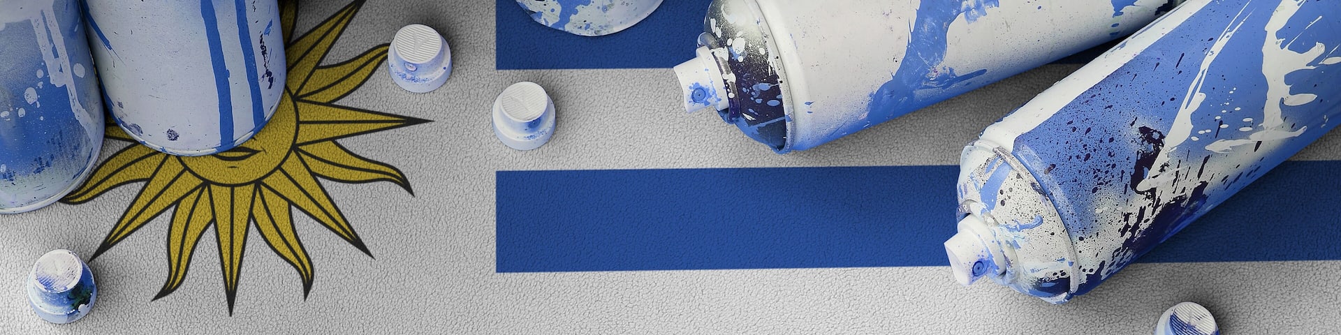 Uruguay flag and few used aerosol spray cans for graffiti painting. Street art culture concept