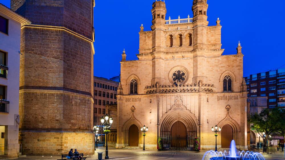 A historic cathedral with twin towers and a fountain in the foreground.
