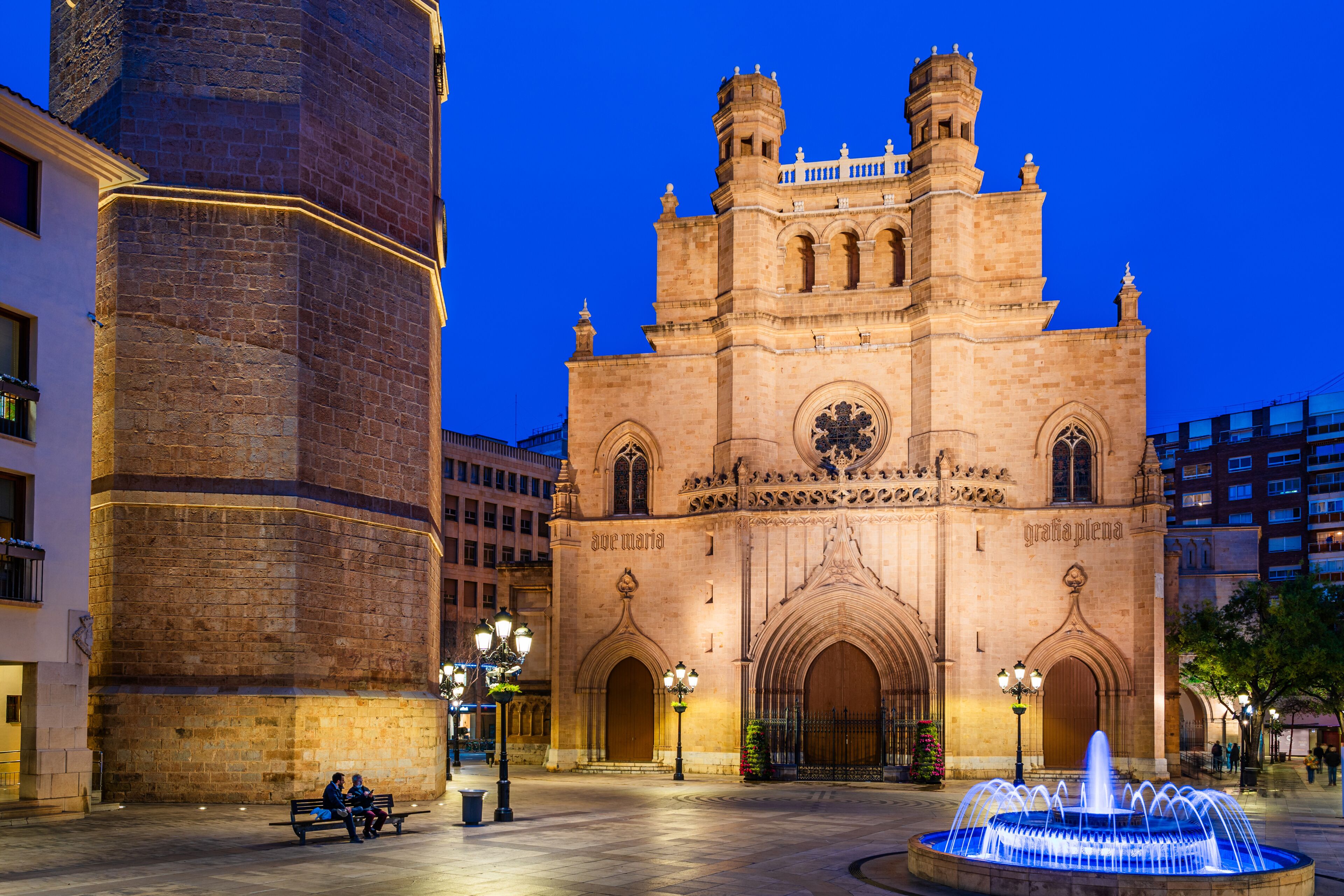 A historic cathedral with twin towers and a fountain in the foreground.