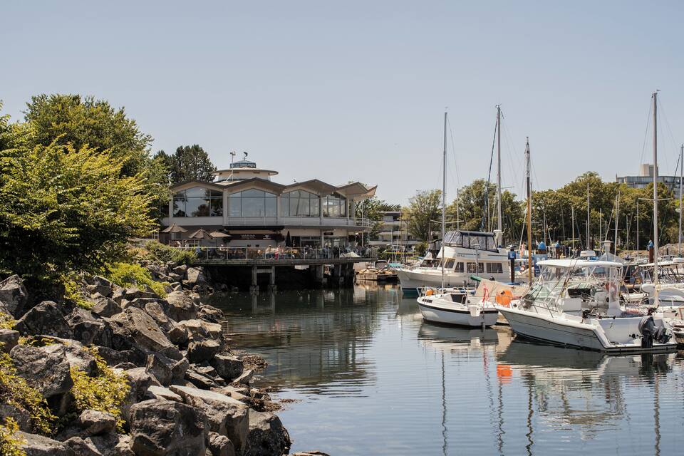 A marina with boats docked, a waterfront building, and rocky shoreline.