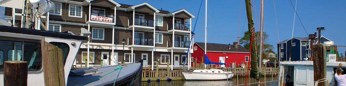 A marina with boats docked, a red building, and a multi-story residential building in the background.
