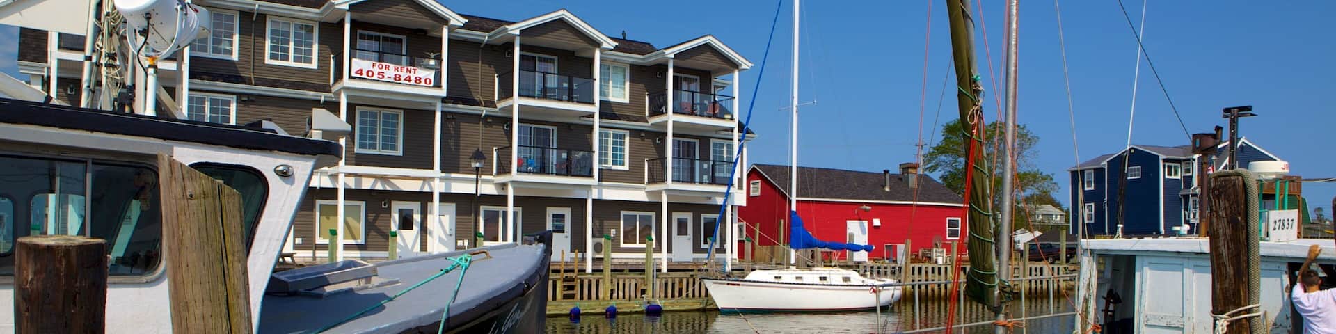 A marina with boats docked, a red building, and a multi-story residential building in the background.