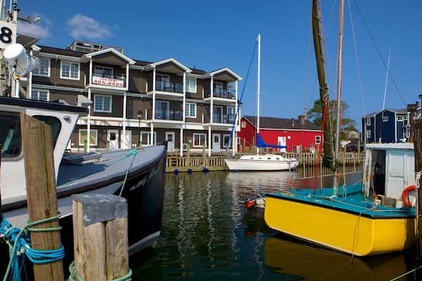 Un port de plaisance avec des bateaux amarrés, un bâtiment rouge et, au fond, un immeuble résidentiel à plusieurs étages.
