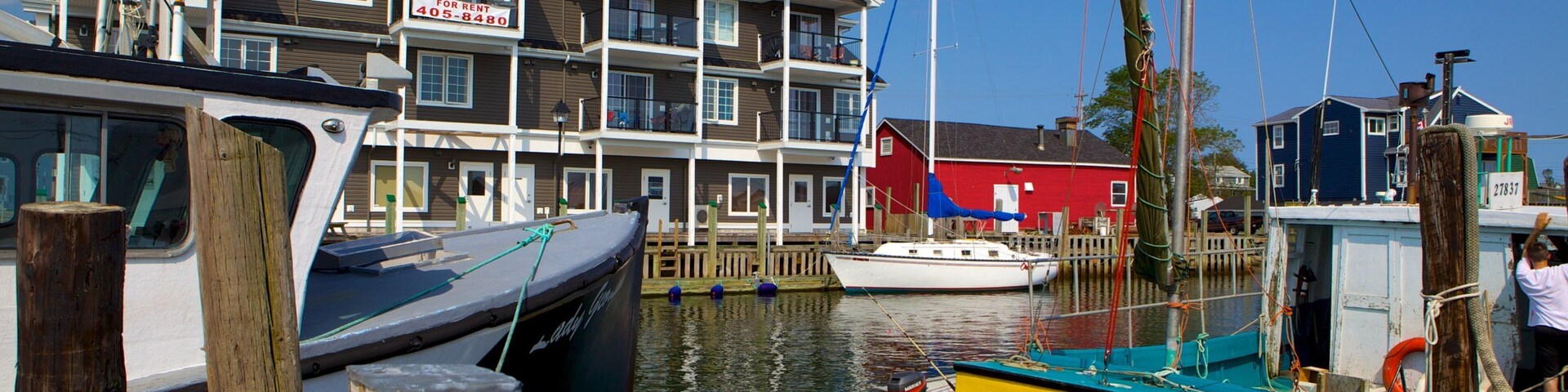 A marina with boats docked, a red building, and a multi-story residential building in the background.