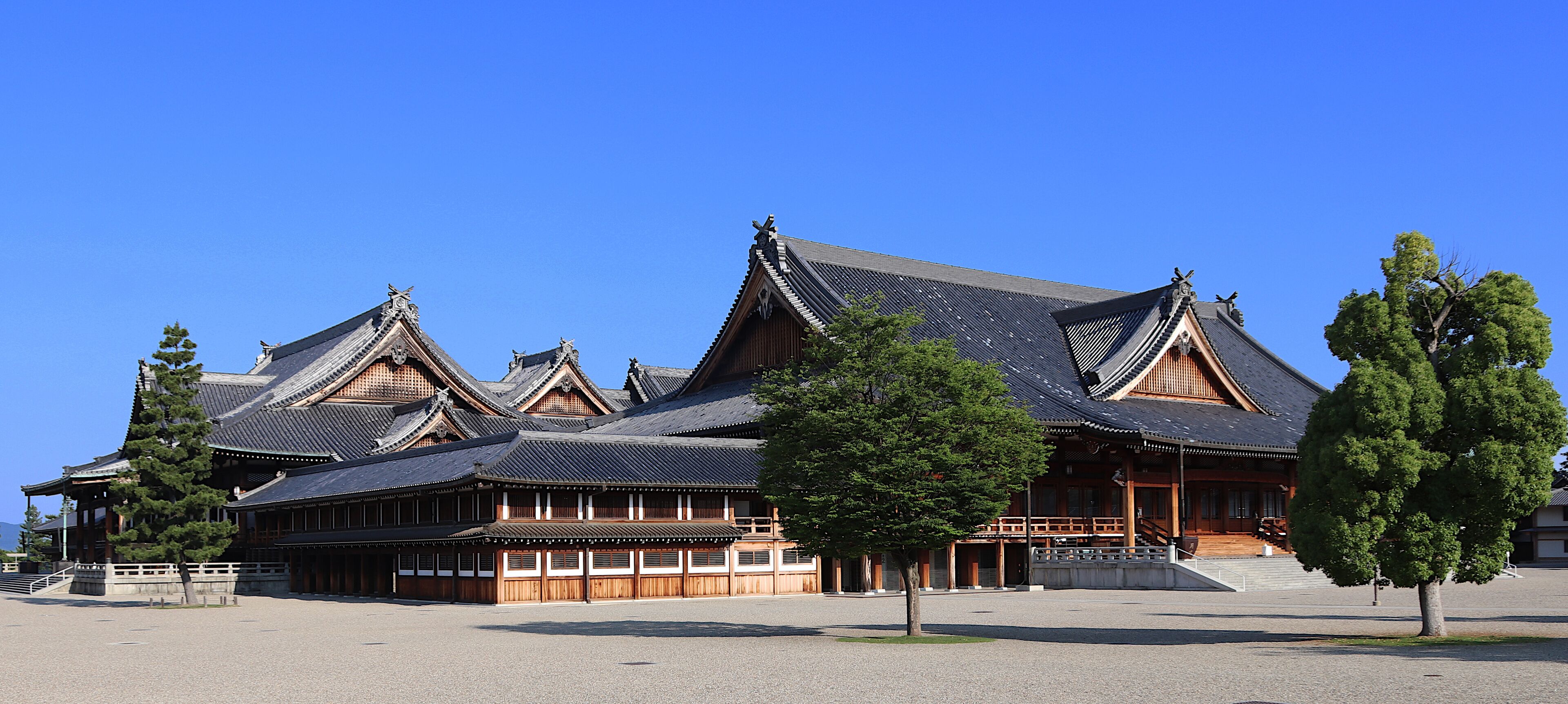 A traditional wooden building with multiple gabled roofs and a large open courtyard.
