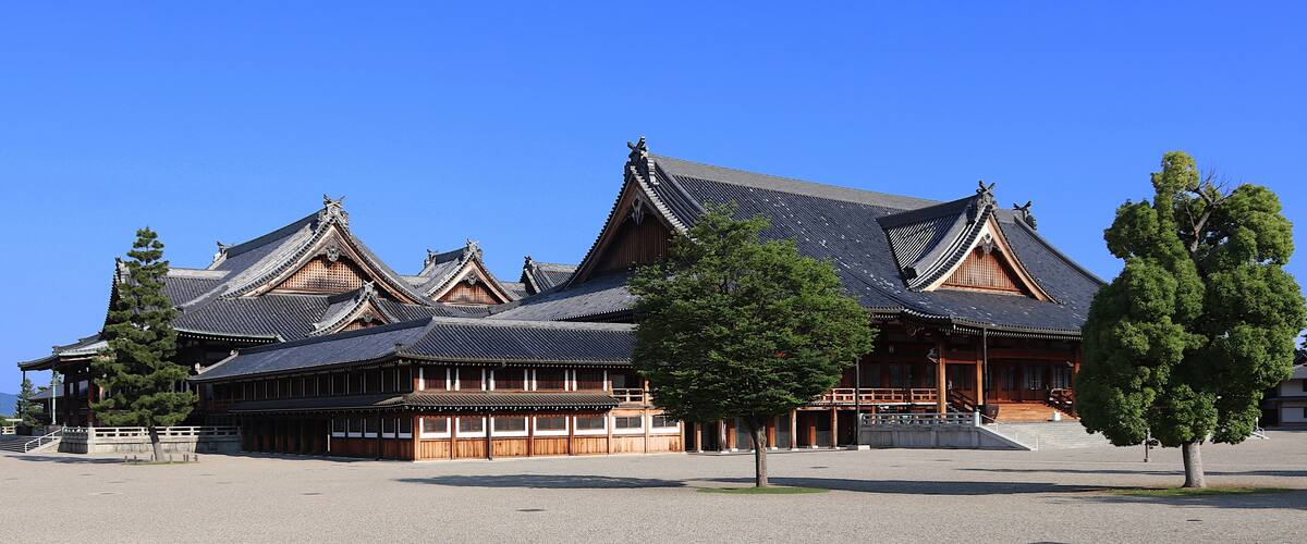 A traditional wooden building with multiple gabled roofs and a large open courtyard.
