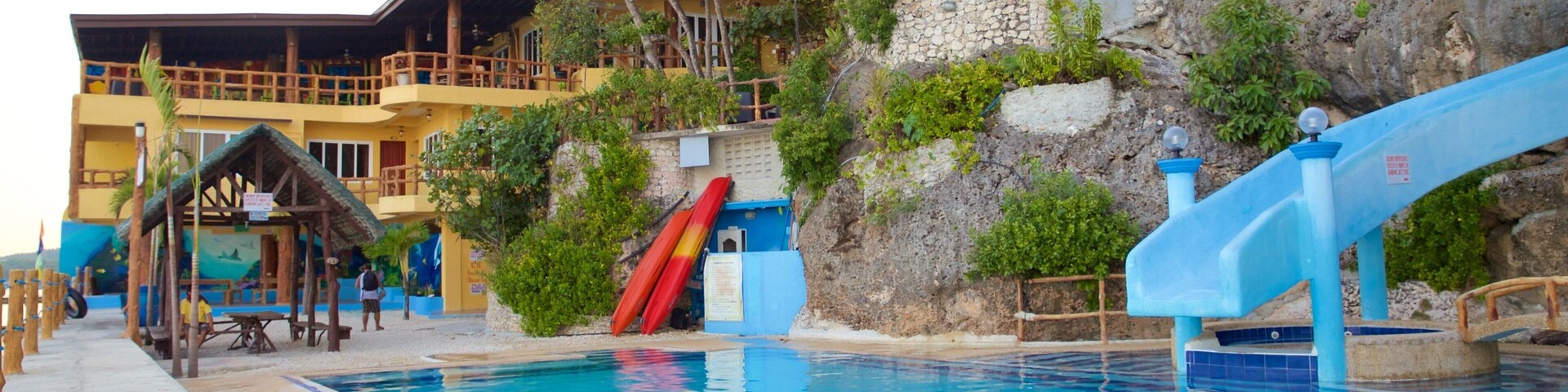 Una piscina con toboganes, una terraza de madera y un edificio con balcones.