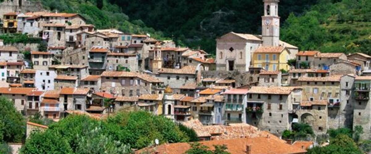 A hillside village with terracotta-roofed buildings and a prominent tower.