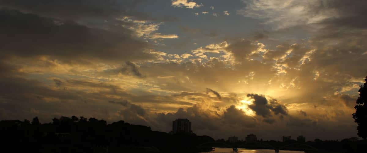 A sunset over a river with a bridge and buildings silhouetted against the sky.