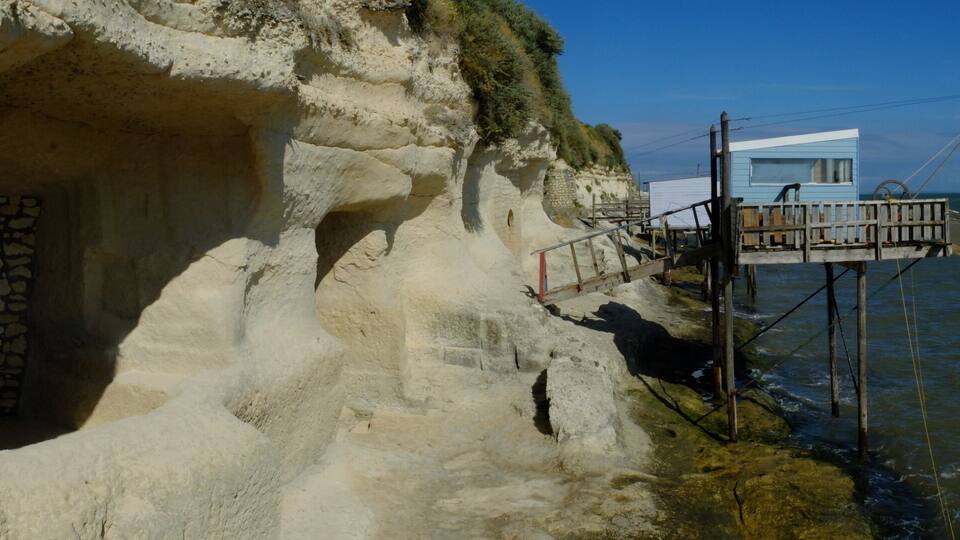 A coastal cave entrance with a wooden platform extending into the sea.