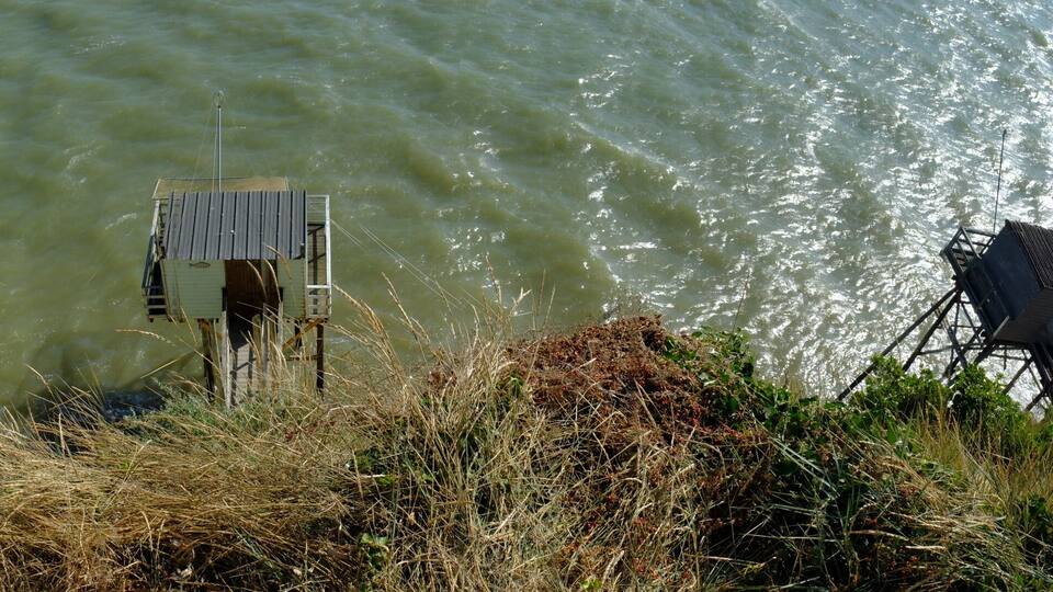 A water tower and a structure on stilts by a body of water.