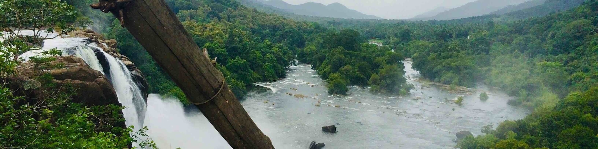 Una cascada se precipita por un acantilado rocoso rodeado de exuberante vegetación y un río que serpentea por el valle.