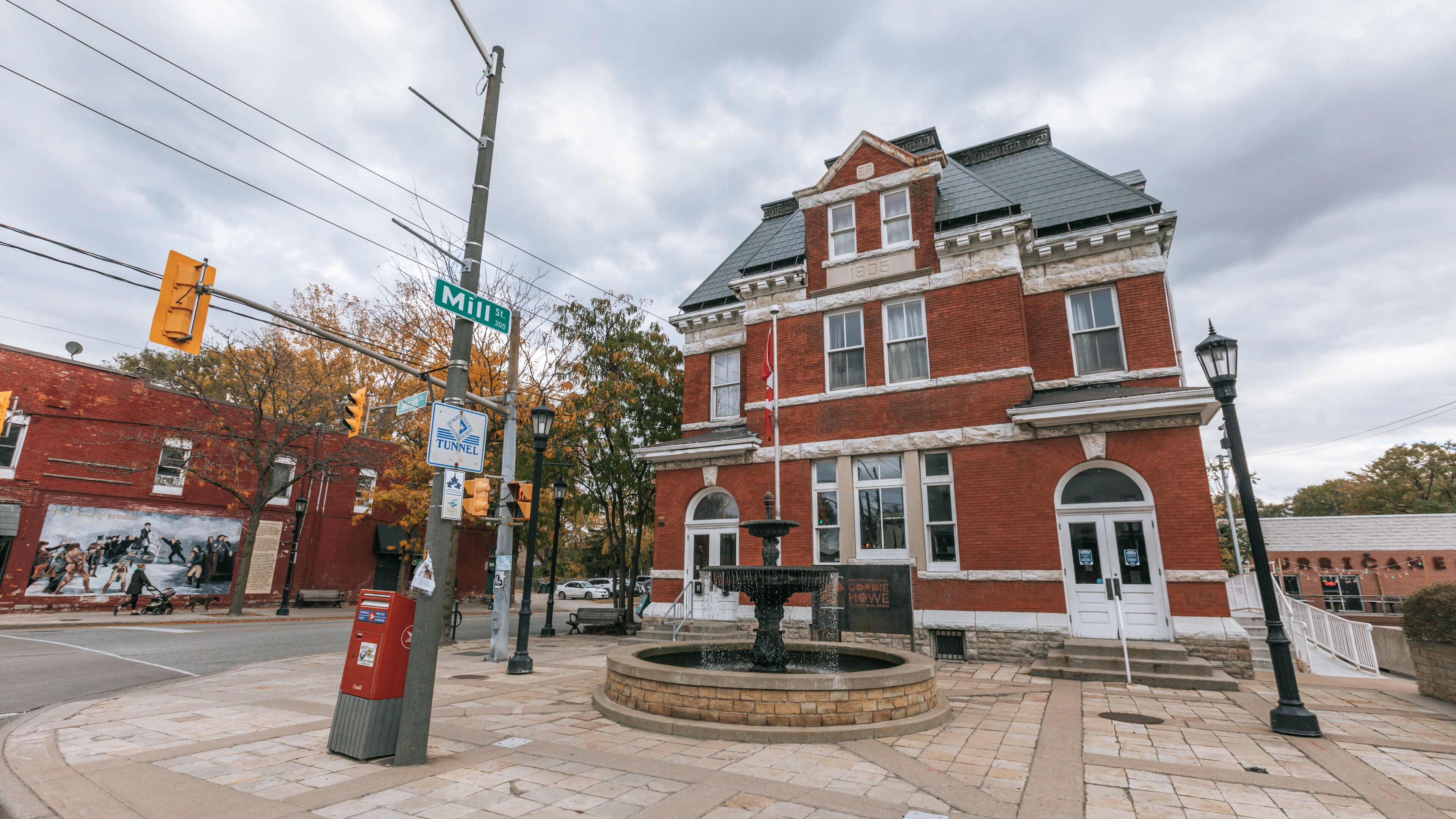 A historic building with a fountain in front, street signs, and a red brick facade.