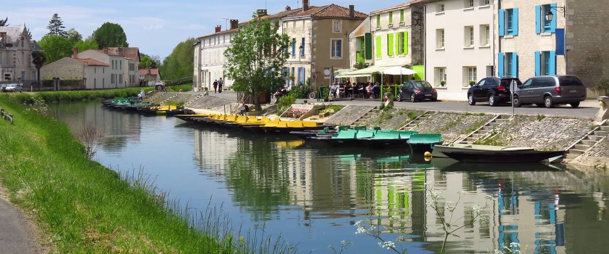A calm river with boats, a café, and traditional buildings along the banks.