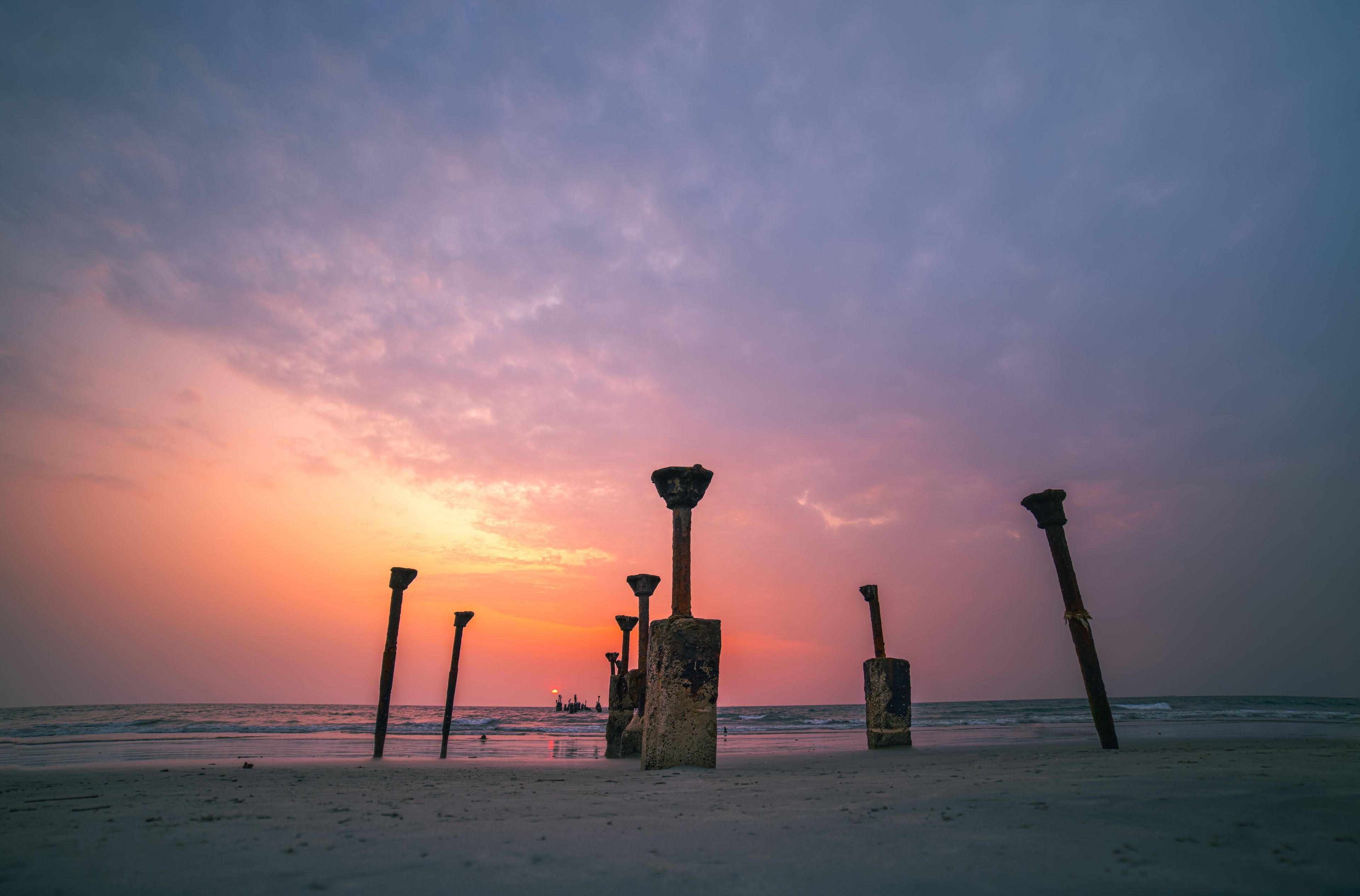 A beach with ancient stone pillars at sunset.