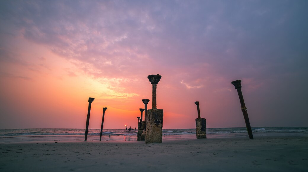 A beach with ancient stone pillars at sunset.