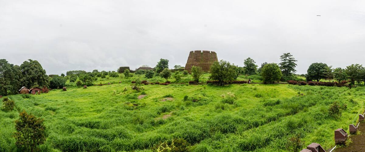 A grassy field with a stone tower and a brick pathway.