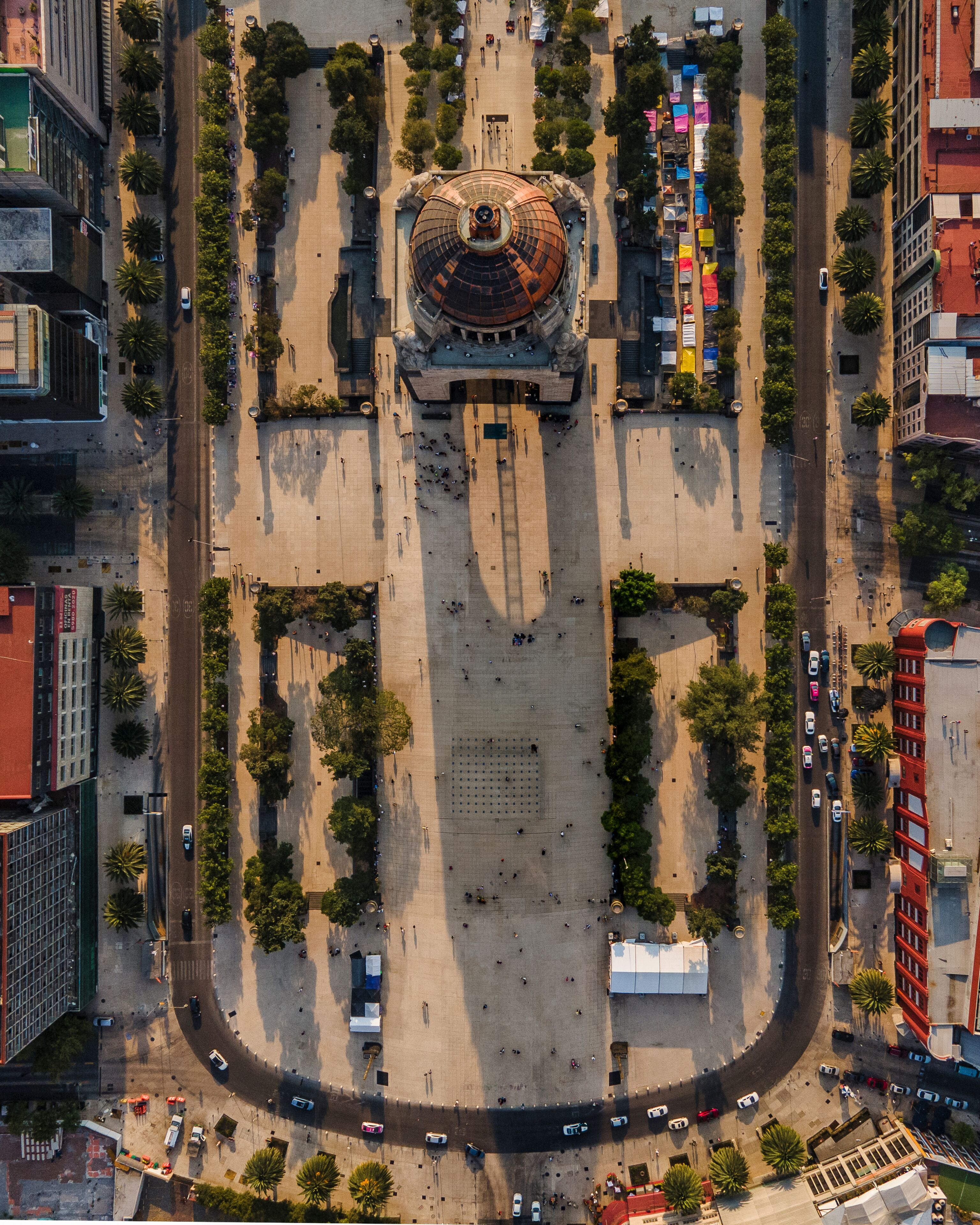 An aerial view of a plaza with a central monument, surrounded by trees and buildings.