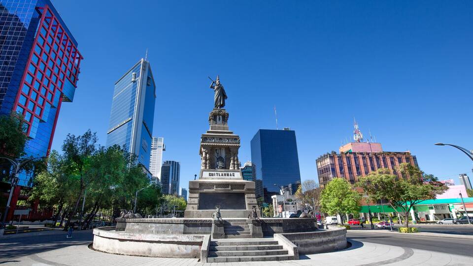 A statue in a plaza with modern buildings in the background.