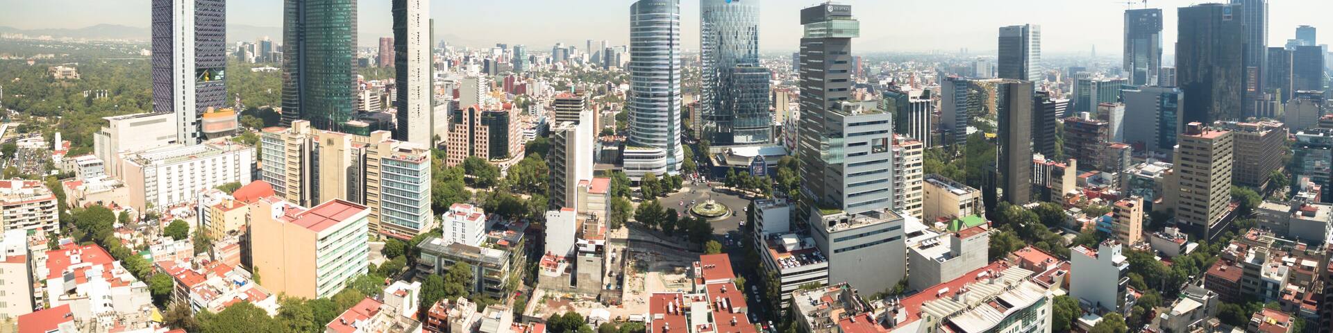 A cityscape with numerous high-rise buildings, a clear blue sky, and a mix of modern and older architecture.