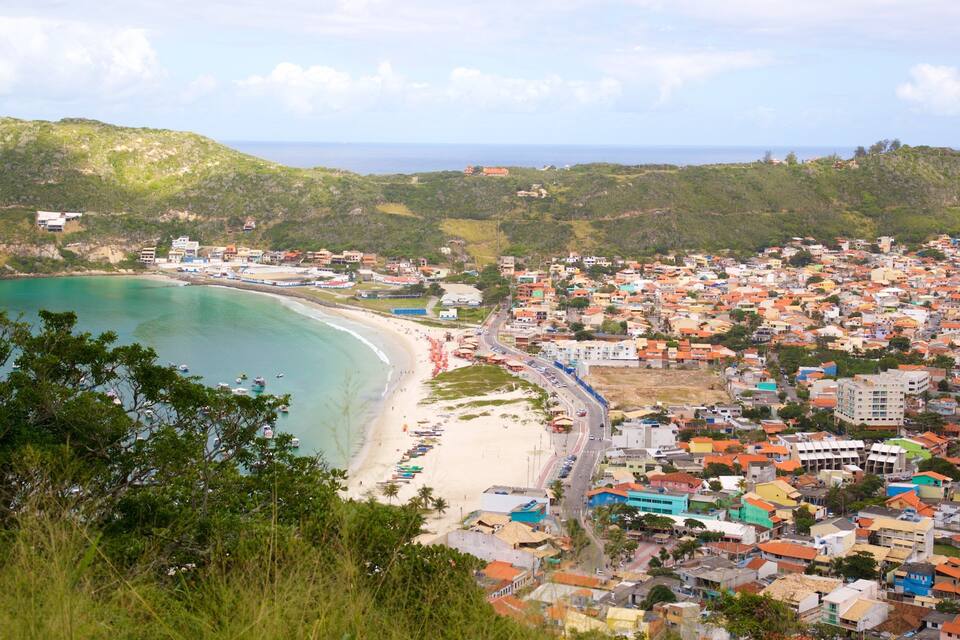 Uma vila costeira com praia, casas e colinas.