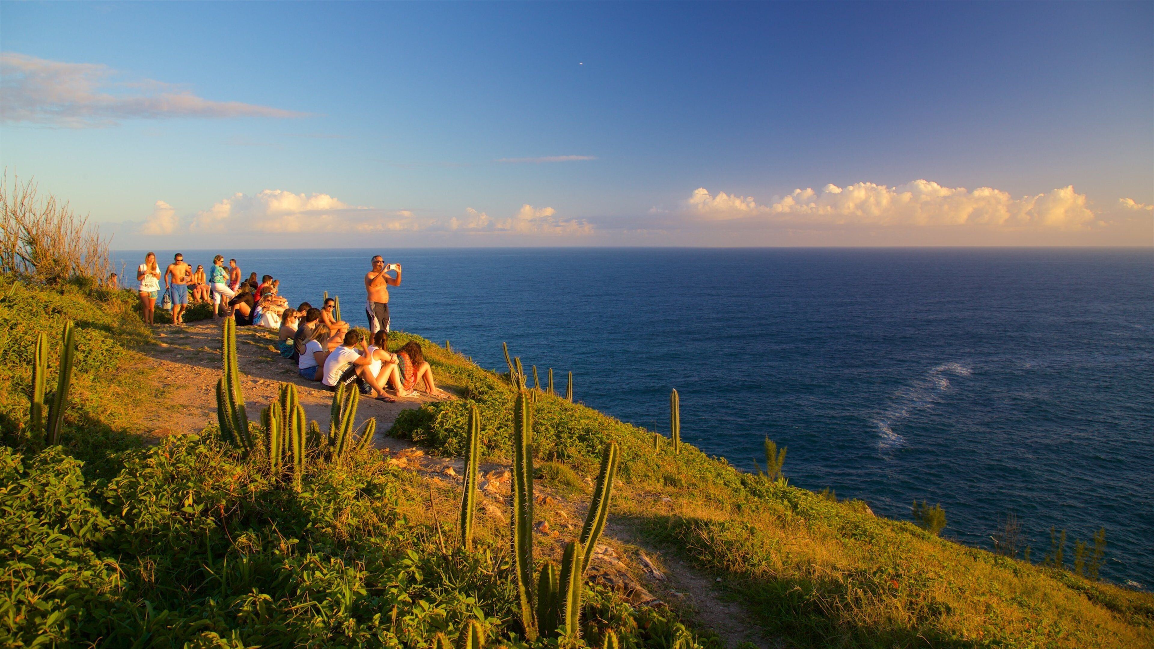 Atalaia Viewpoint which includes a sunset and general coastal views as well as a small group of people