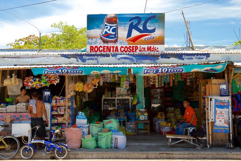 A small roadside shop with a sign for Rocenta CoSep Gen. Mdsce. and a large RC Cola advertisement.
