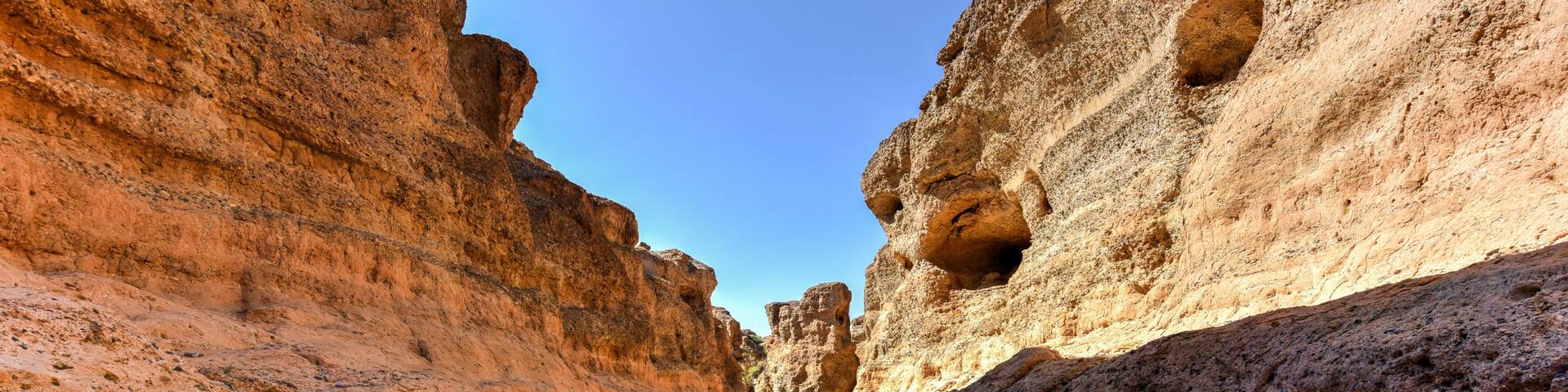 A canyon with layered rock formations and a clear blue sky.