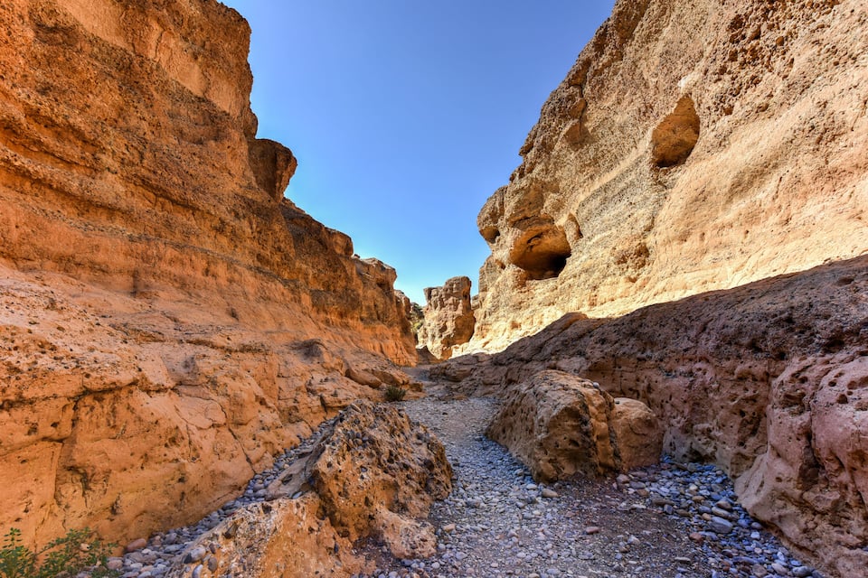 A canyon with layered rock formations and a clear blue sky.