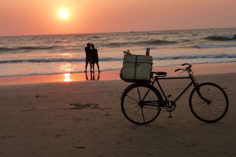 A bicycle with a storage box on a beach at sunset.