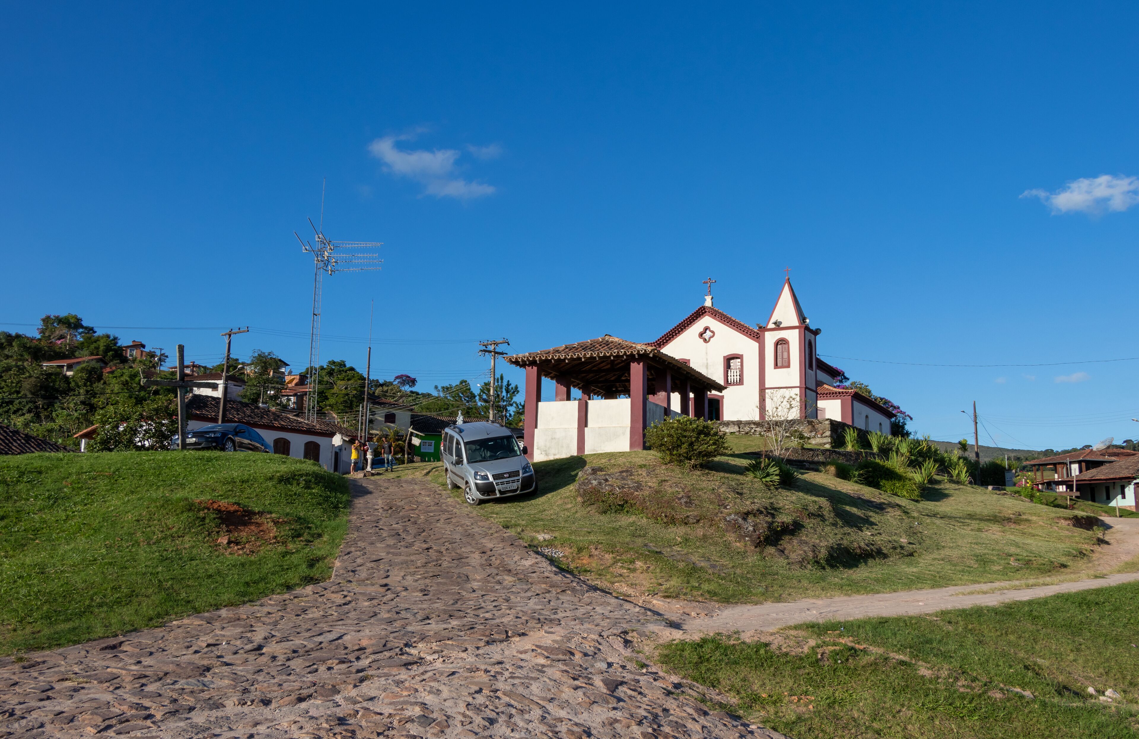 A cobblestone path leading to a church with a red-tiled roof and a bell tower.