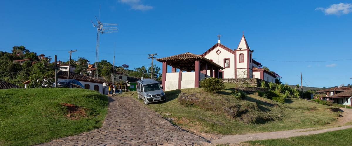 A cobblestone path leading to a church with a red-tiled roof and a bell tower.